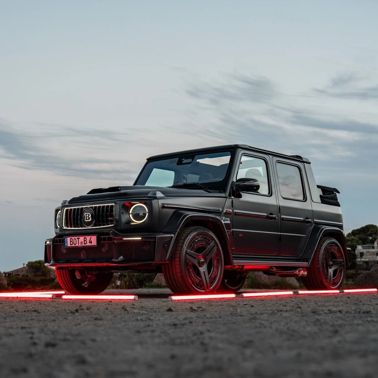 Black BRABUS G-Class at dusk, lit by red light tubes on the ground. BRABUS automotive imagery, not the residential project.