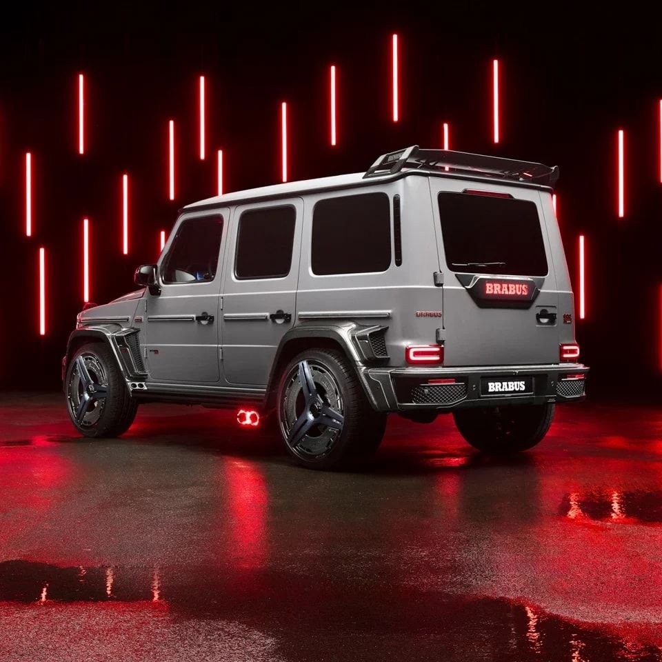 Silver BRABUS G-Class in a studio with vertical red neon lights and a wet reflective floor. BRABUS automotive imagery, not the residential project.